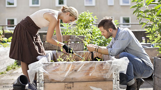 Mann und Frau führen Gartenarbeiten in einem Hochbeet durch