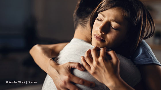 Frau nimmt eine trauernde Person in den Arm
