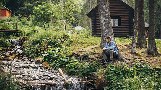 Wanderer sitzt im Wald bei einem Bergbach