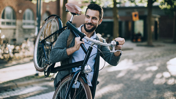 Mann trägt sein Fahrrad über der Schulter