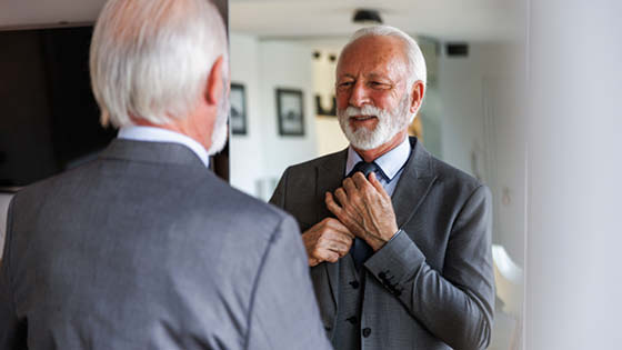 älterer Mann steht vor Spiegel