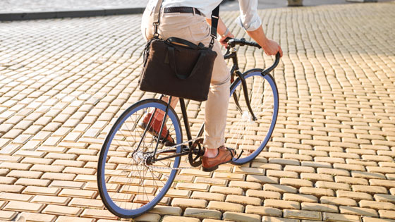 Mann im Business-Outfit und mit Laptoptasche am Fahrrad