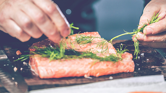 Fischfilet wird mit Kräutern gewürzt