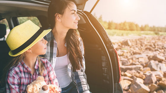 Mama und Tochter sitzen im parkenden Auto und schauen in die Ferne