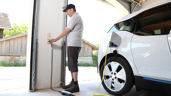 Mann tankt E-Auto an der Ladestation auf