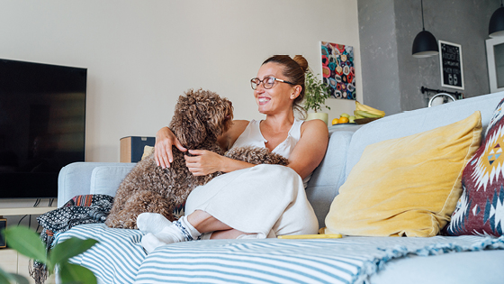 Frau und Hund sitzen auf der Couch im Wohnzimmer