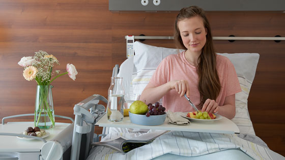 frau im krankenbett beim obst schneiden