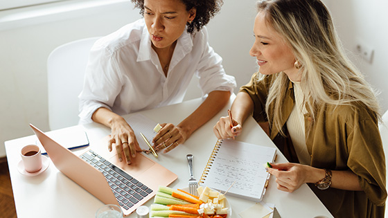 Zwei Frauen im Büro vor Laptop.