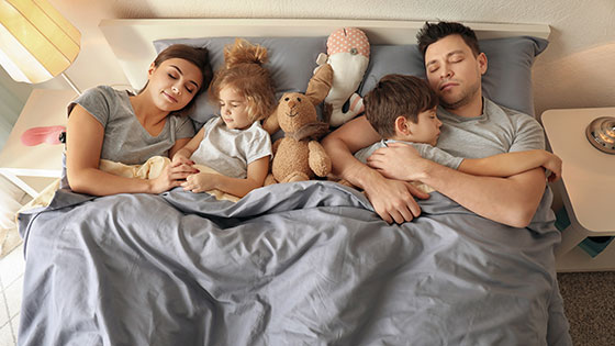 Familie mit zwei Kindern liegt im Bett und schläft