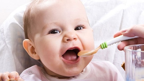 Baby wird mit Brei gefüttert.