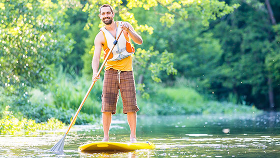 Mann im Wasser beim Stehpaddeln