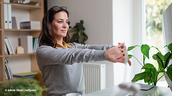 Frau macht Bewegungsübungen im Home Office