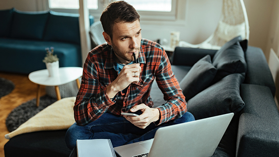 Mann sitzt vor dem Laptop und rechnet
