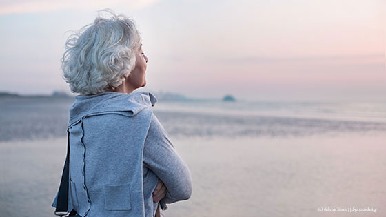 Damit mit grauen Haaren schaut am Strand in die Ferne