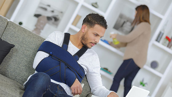 junger Mann mit Armbinde sitzt auf der Couch