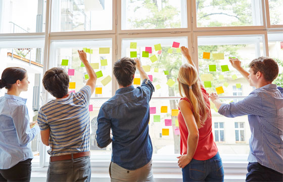 Fünf Personen vor Fenster mit farbigen Post It´s