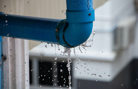 Undichte Wasserleitung mit austretendem Wasser an einer Rohrverbindung.