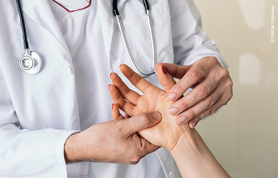 Arzt untersucht die Hand von einer Patientin