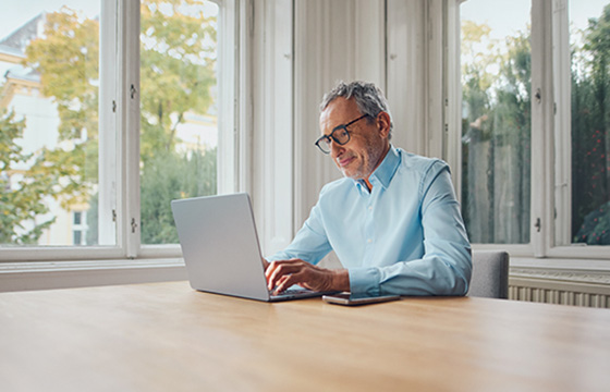 Mann sitzt arbeitet am Laptop