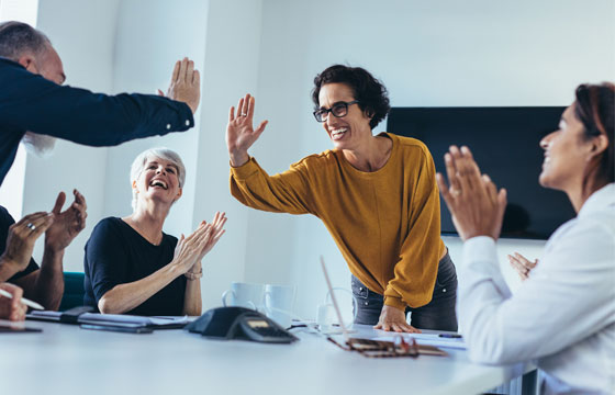 Personen schlagen über Tisch in erhobene Hand ein