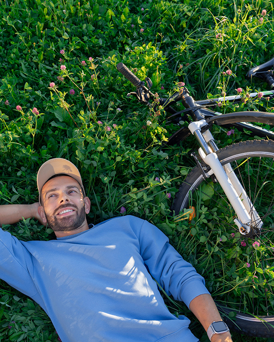 Ein Mann und sein Fahrrad liegen gemütlich auf einer grünen Wiese