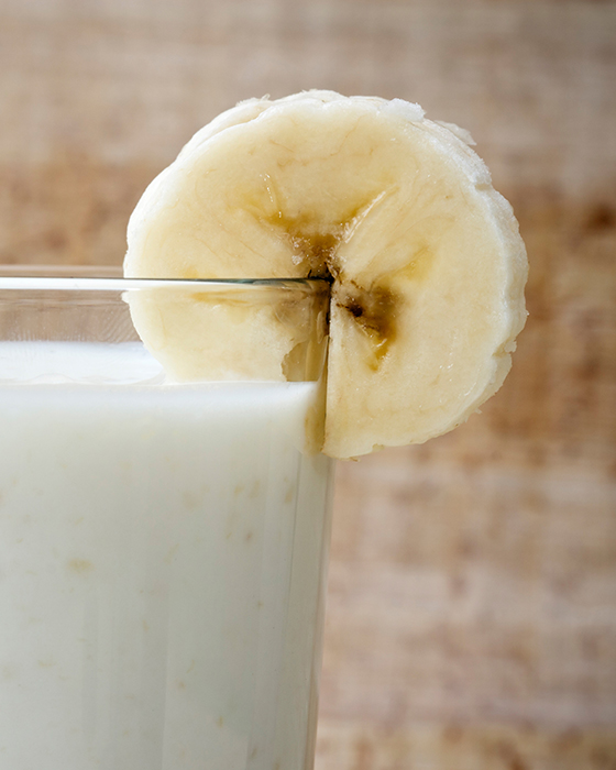 Glas mit weißem Milchgetränk, dekoriert mit einer Bananenscheibe am Glasrand