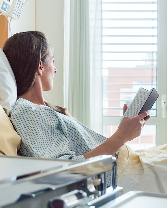 Frau liest im Krankenbett im Spital