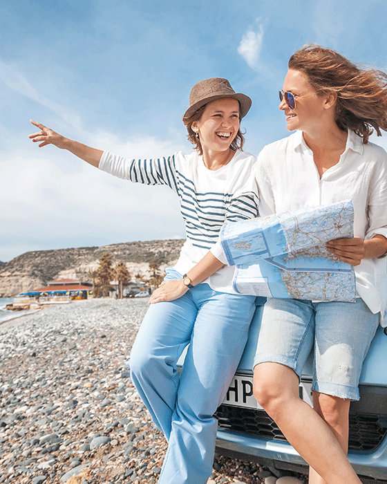 Zwei Frauen sitzen mit Straßenkarte auf der Motorhaube