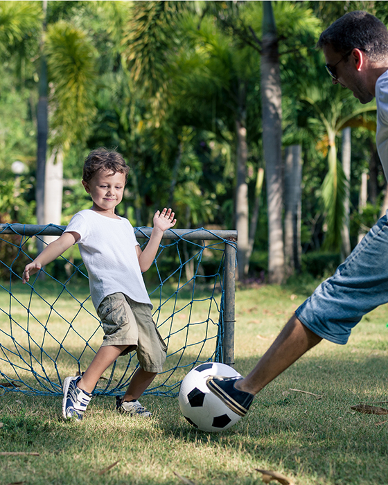 Vater und Kind beim Fußball spielen in der Wiese