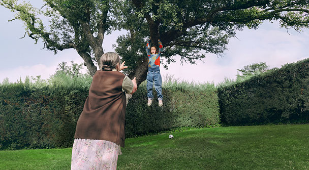 Kind hängt von Baum im Garten. Oma eilt herbei.