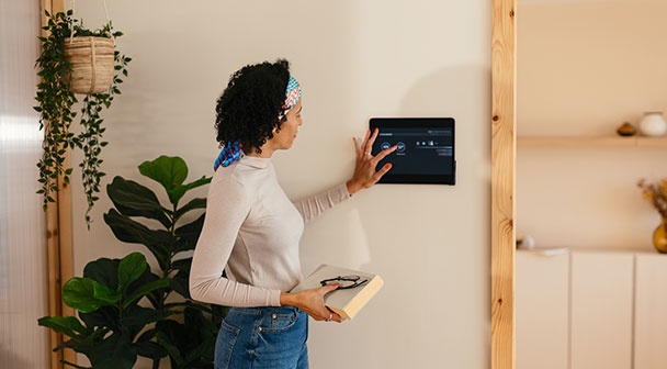 Eine Person bedient das Wohntechnikgerät an der Wand