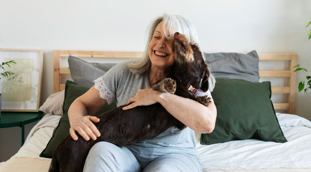 Lebendige ältere Dame spielt fröhlich mit Ihrem Hund
