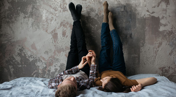 Paar liegt auf dem Bett und denkt über Vorsorge nach