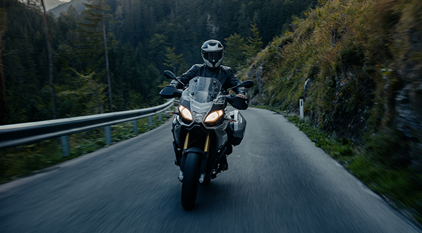 Motorradfahrer auf einer Bergstraße im Wald