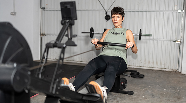 frau in in der fitnessgarage am rudergerät