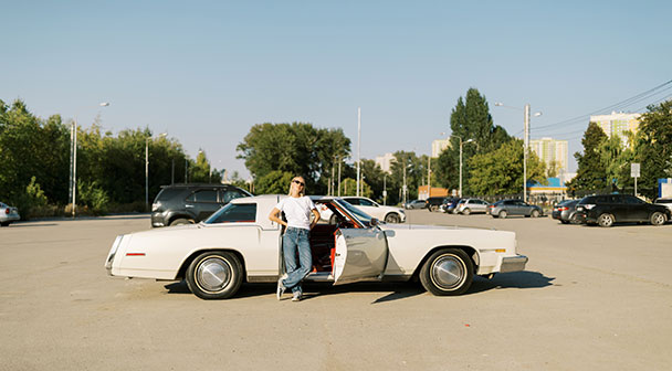 Frau steht an der offenen Tür ihres Oldtimers