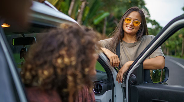 Gruppe von Jugendlichen stehen rund ums Auto und plaudern