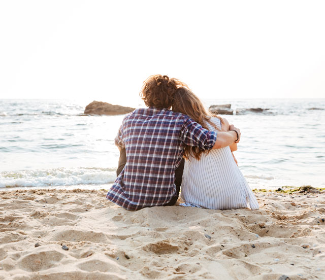 Mann und Frau sitzen umarmt im Strand