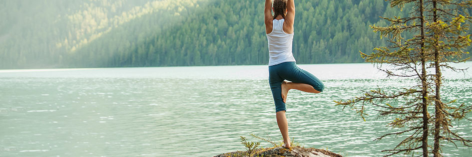 Frau macht Yoga am See in den Bergen