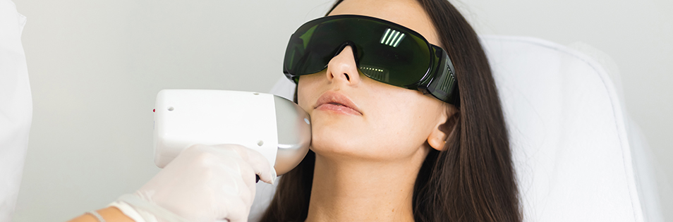 Kosmetische Lichtbehandlung im Gesichtsbereich mit Schutzbrille und medizinischem Handgerät.