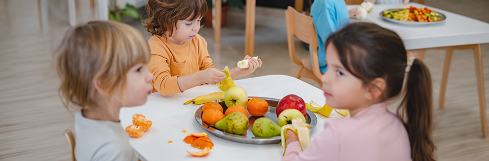 Kinder essen Obst an einem Tisch