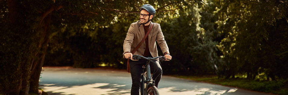 Person fährt mit dem Fahrrad auf einem Weg durch eine Grünanlage. Symbolbild für nachhaltige Mobilität.