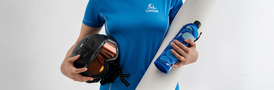Person hält Skihelm, Yogamatte und Trinkflasche
