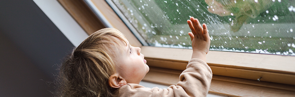 Kind schaut aus dem Fenster - es schneit