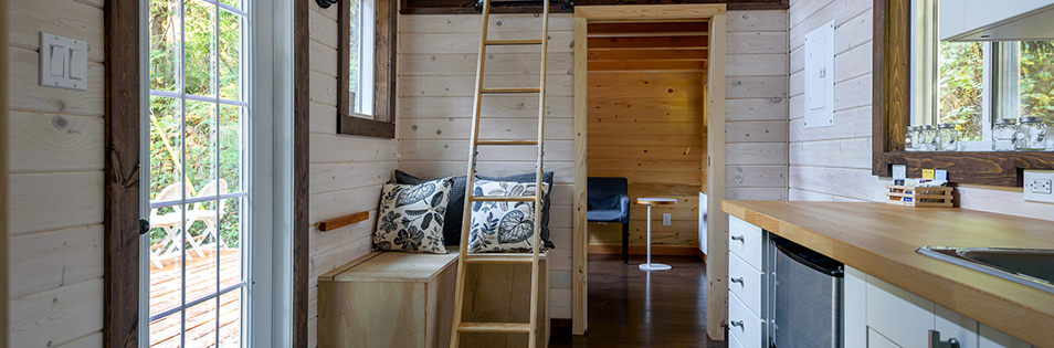Innenraum eines Tiny Houses mit Sitzbereich, Leiter und Küchenzeile.