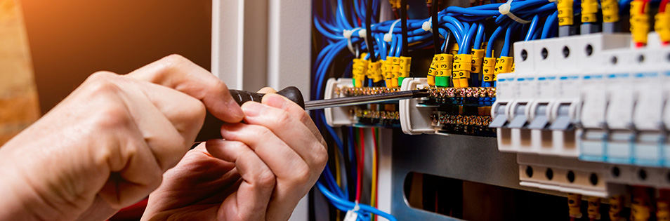 Hand mit Schraubenzieher an einer Technik-Anlage