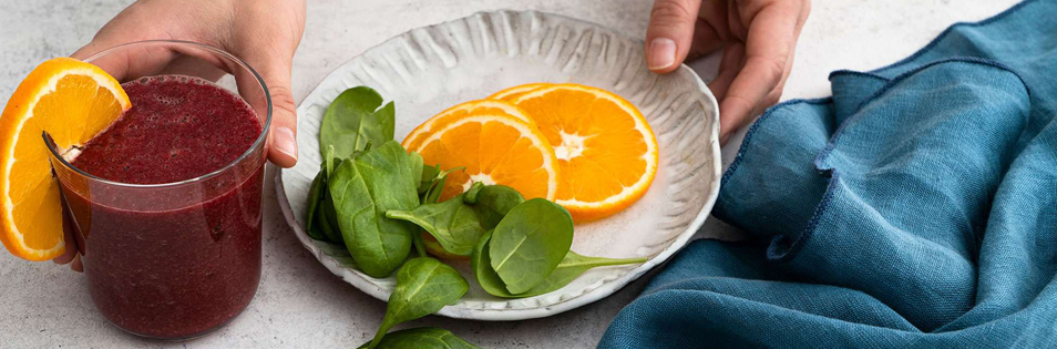 frisch gepresster saft, orangenscheiben und blattspinat auf einem teller