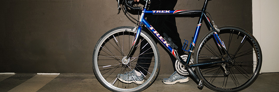 Fahrrad steht in einem Innenraum, eine Person hält das Fahrrad am Lenker.