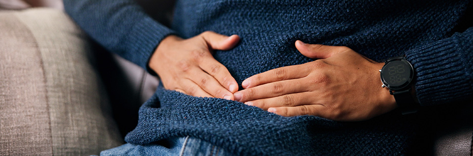 Mann hält sich die Hand an den Bauch - Bauchschmerzen