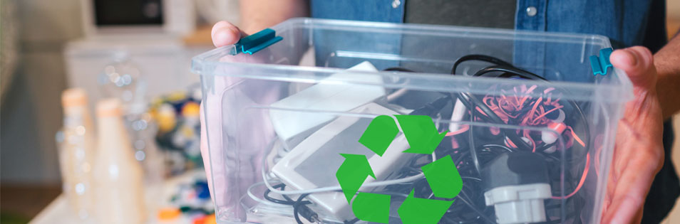 Person hält eine transparente Box mit ausrangierten Kabeln, Ladegeräten und elektronischen Kleingeräten. Auf der Box befindet sich ein Recycling-Symbol.